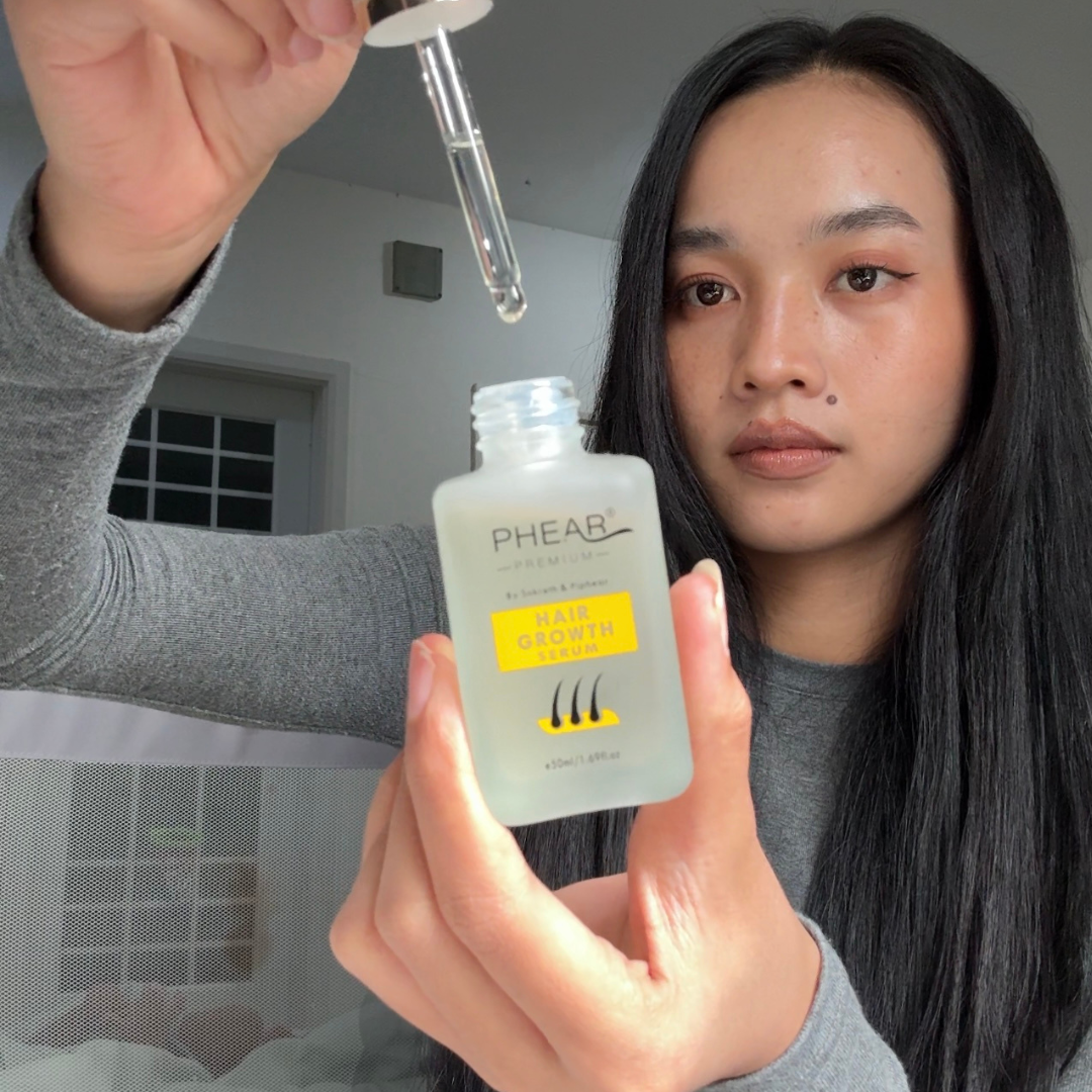 Person holding a bottle labeled 'PHEAR' with a dropper above, against a neutral background.