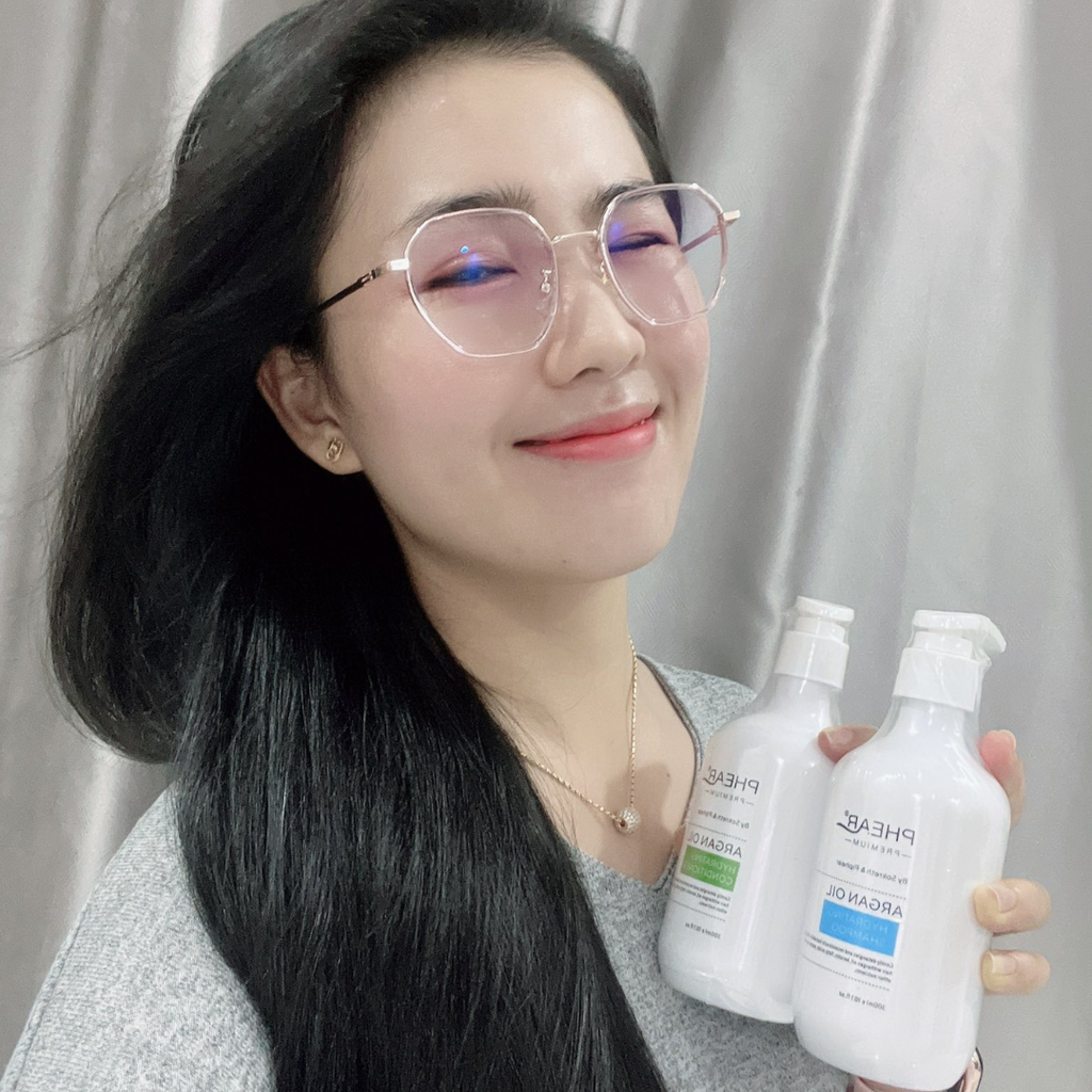 Woman holding two bottles of hair care products against a neutral background