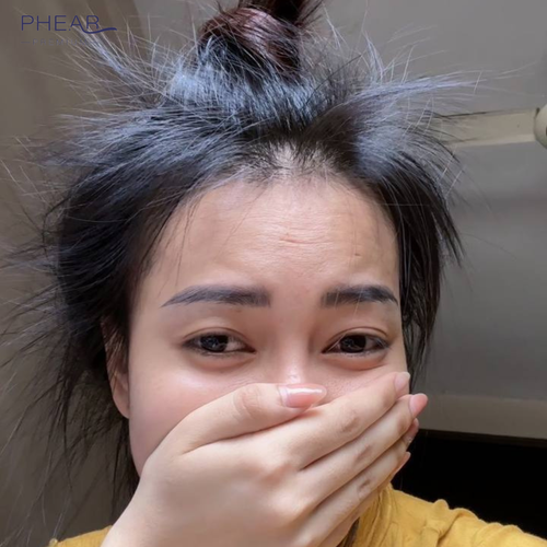 Person with long hair covering face, wearing a yellow shirt